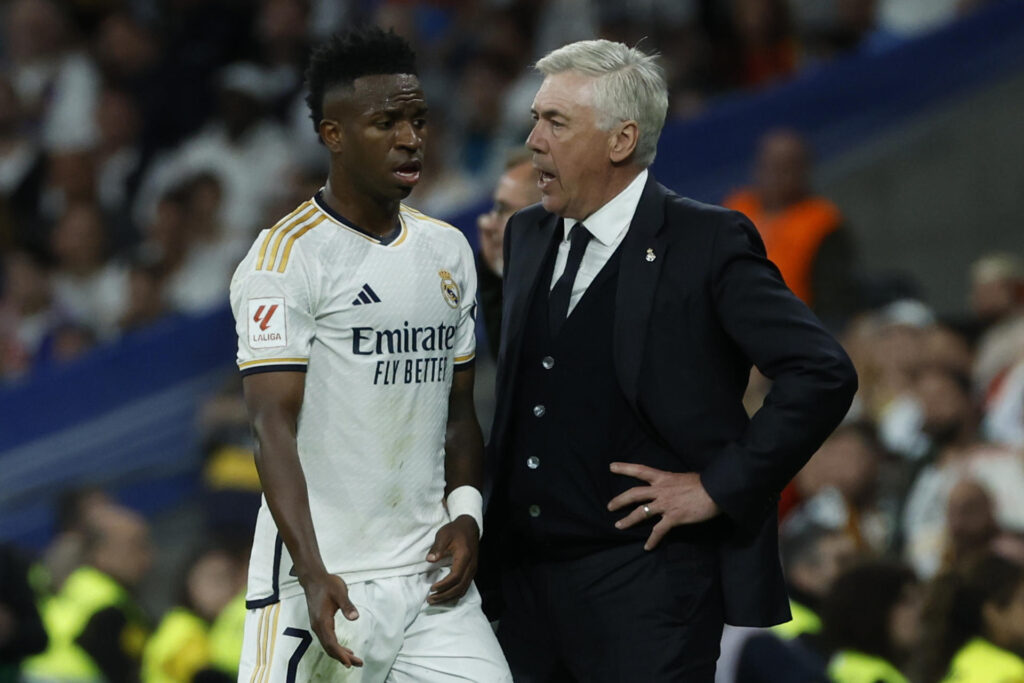 El entrenador italiano del Real Madrid, Carlo Ancelotti (dcha), conversa con el brasileño Vinicius Jr., durante el partido de la jornada 32 de LaLiga EA Sports entre Real Madrid y FC Barcelona, disputado este domingo en el estadio Santiago Bernabéu de Madrid. EFE/Juanjo Martín