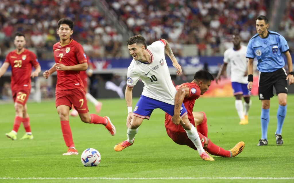 El delantero estadounidense Christian Pulisic (C) y el centrocampista boliviano Héctor Cuellar (d) en la Copa América 2024. EFE/EPA/KEVIN JAIRAJ