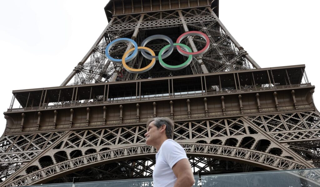 Paris (France), 25/07/2024.- A person walks past the Eiffel Tower with the Olympic rings prior to the opening ceremony of the Paris 2024 Olympic Games, in Paris, France, 25 July 2024. The opening ceremony of the Paris 2024 Olympic Games will begin on 26 July with a nautical parade on the Seine river and end on the protocol stage in front of the Eiffel Tower. (Francia, Colombia, París) EFE/EPA/MAXIM SHIPENKOV