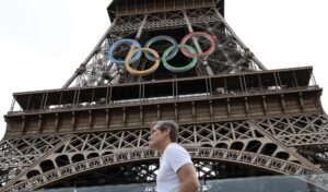 Paris (France), 25/07/2024.- A person walks past the Eiffel Tower with the Olympic rings prior to the opening ceremony of the Paris 2024 Olympic Games, in Paris, France, 25 July 2024. The opening ceremony of the Paris 2024 Olympic Games will begin on 26 July with a nautical parade on the Seine river and end on the protocol stage in front of the Eiffel Tower. (Francia, Colombia, París) EFE/EPA/MAXIM SHIPENKOV