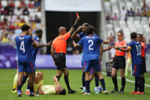 El árbitro Adel Al Naqbi (c) le saca la tarjeta roja al dominicano Edison Azcona (d) tras una acción contra Pau Cubarsí (en el suelo) durante el partido del Grupo C de fútbol masculino de los Juegos Olímpicos de París 2024 disputado este sábado en el Estadio de Burdeos. (Dominicana) EFE/ M. Reino