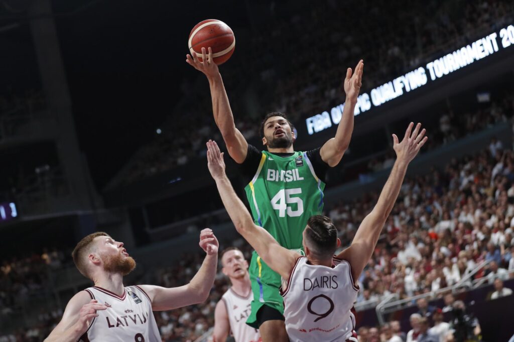 Los jugadores letones Davis Bertans (I) y Dairis Bertans defienden Joao Cardoso de Brasil (c) durante el preolímpico de Riga en Letonia. EFE/EPA/TOMS KALNINS