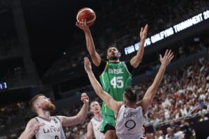 Los jugadores letones Davis Bertans (I) y Dairis Bertans defienden Joao Cardoso de Brasil (c) durante el preolímpico de Riga en Letonia. EFE/EPA/TOMS KALNINS