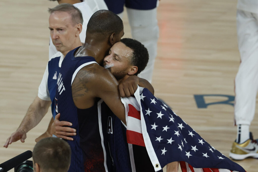 Stephen Curry (d), base estrella de Estados Unidos, fue registrado este sábado, 10 de agosto, al abrazar a su compañero Kevin Durant, luego de ganar la final del baloncesto de los Juegos Olímpicos 2024, en el coliseo South París Arena de la capital francesa. EFE/Juanjo Martin
