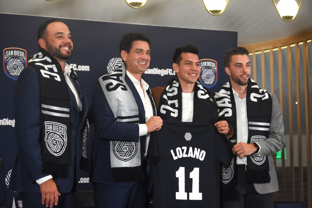 El mexicano Hirving 'Chucky' Lozano (2-d) posa con la bufanda y la camiseta del San Diego FC junto al director ejecutivo del club Tom Penn (2-i), el director de estrategia del mismo Tyler Heaps (d) y el presidente de la Banda Sycuan de la Nación Kumeyaay Cody Martínez (i). EFE/Priscila Chávez Flores