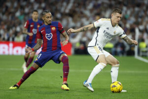 El centrocampista alemán del Real Madrid Toni Kroos (d) disputa un balón ante el delantero brasileño del FC Barcelona Raphinha (i) durante el partido de la jornada 32 de LaLiga EA Sports entre Real Madrid y FC Barcelona (El Clásico), en el estadio Santiago Bernabéu de Madrid. EFE/ Juanjo Martín