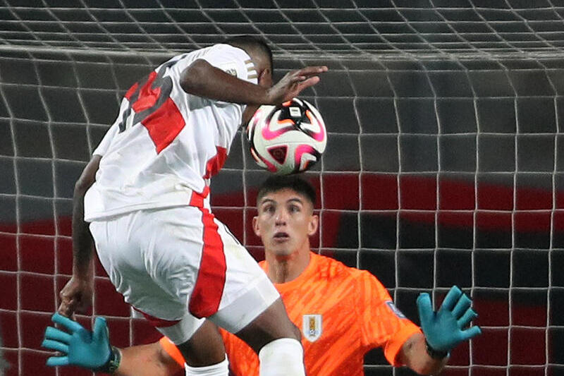 Miguel Araujo (i) de Perú cabecea un balón ante Sergio Rochet de Uruguay. EFE/ Paolo Aguilar