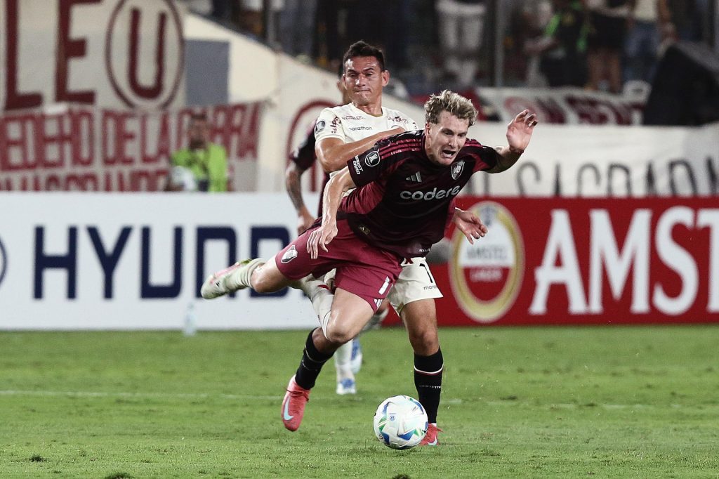Jairo Vélez (atrás) de Universitario disputa el balón con Facundo Colidio de River Plate este miércoles, durante un partido de la fase de grupos de la Copa Libertadores. EFE/ STR