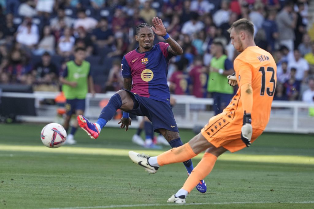 El delantero brasileño del Barcelona Raphinha (i) presiona al portero estonio del Valladolid Karl Hein durante el partido de LaLiga que disputaron ambos conjuntos el 31 de agosto en el estadio Olímpico Lluis Companys. EFE/ Alejandro Garcia
